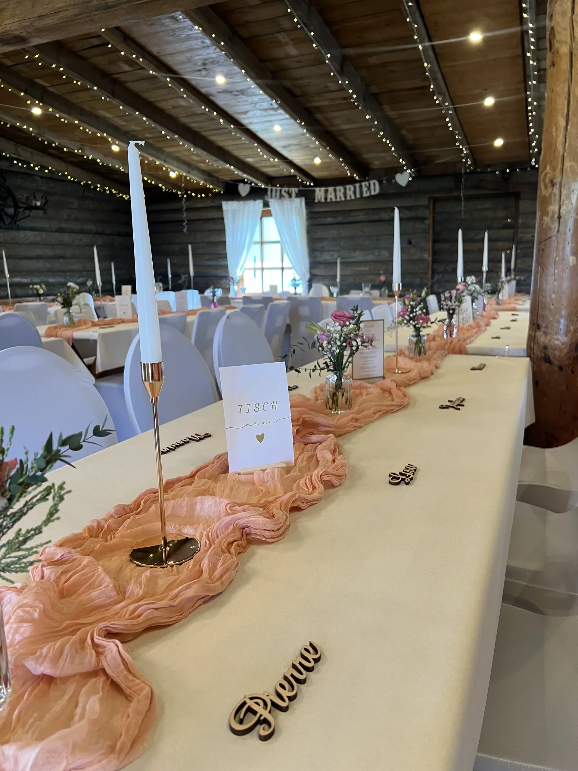 Lange Tafel mit apricotfarbenem Tischläufer, Kerzen und Namensschildern aus Holz